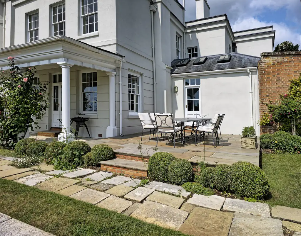 Wide natural stone terrace with patio furniture outside a large home